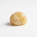 Illustrative yellow calcite tumble stone on a white background